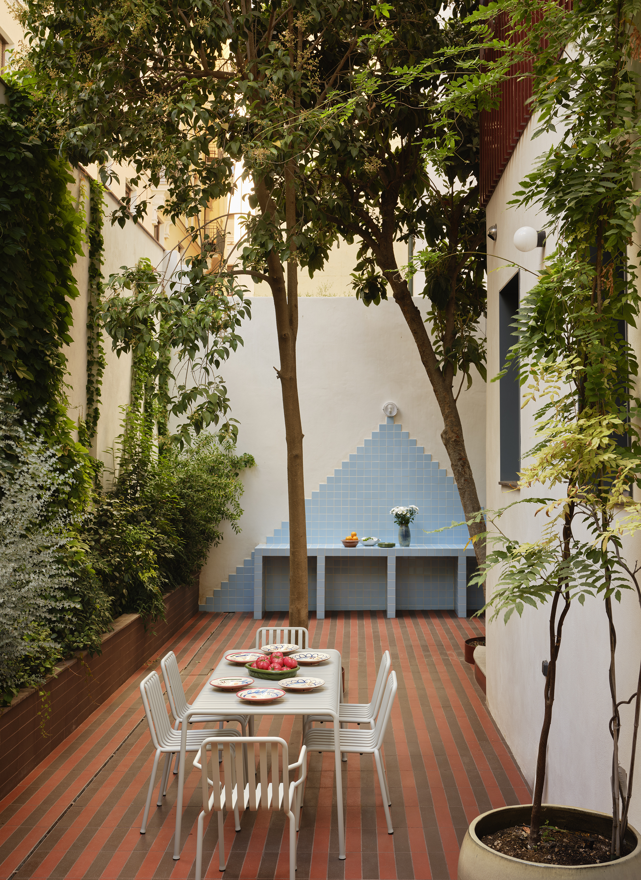 outdoor dining area with tall trees and striped ceramic tiles