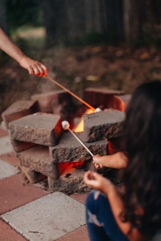 children toasting marshmallows over a brick DIY fire pit