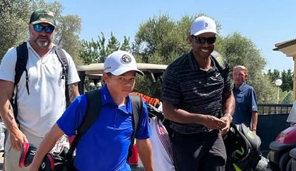 Tiger and Charlie Woods walk through the club with their golf bags