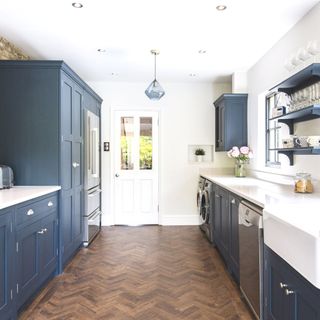 galley kitchen with blue cabinetry and wooden herringbone flooring