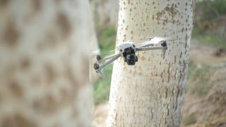 DJI Air 3S drone weaving between two trees