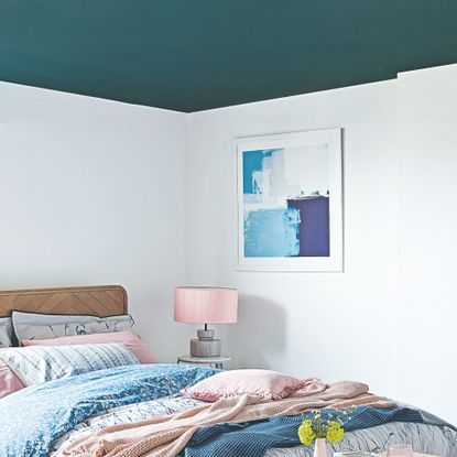 A bedroom with a contrasting blue painted ceiling