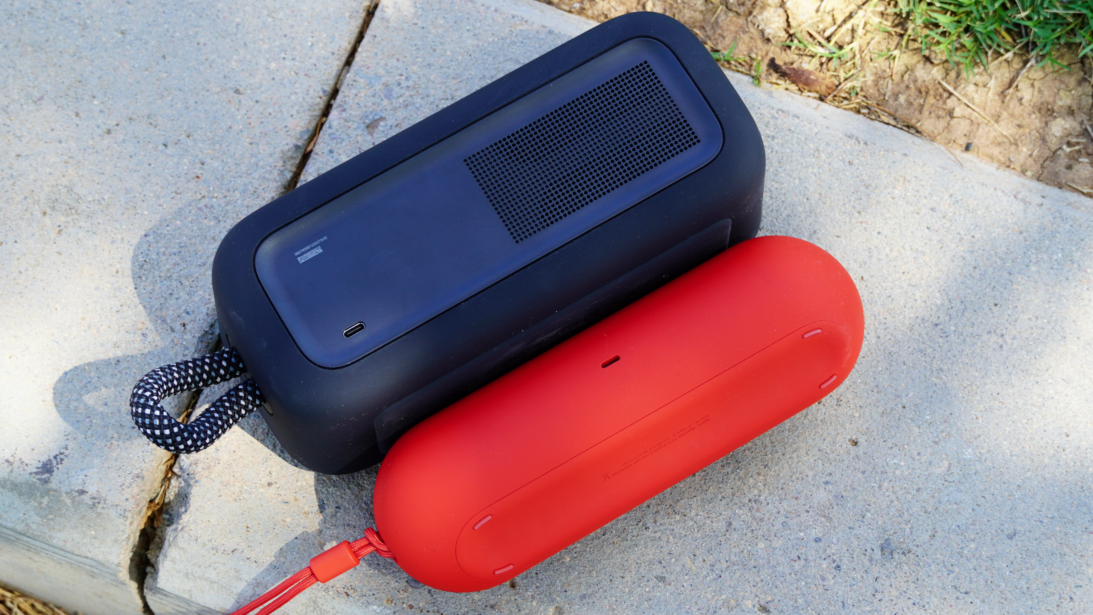 The back side and USB-C ports on the Bose SoundLink Plus (black) and the Beats Pill (red).