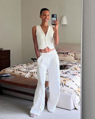 Woman wearing a white vest and matching trousers.