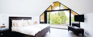 Bifold doors open to a balcony in this bedroom with vaulted ceilings