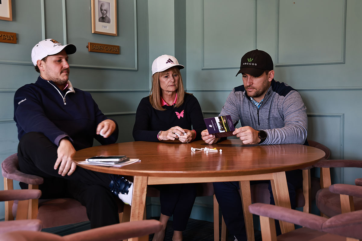 Nick Bonfield, Alison Root and Sam De'Ath sitting in the clubhouse at a golf course around a table with their hats on