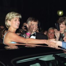 Princess Diana sticking her head out of a limo sunroof and shaking hands with fans in 1997