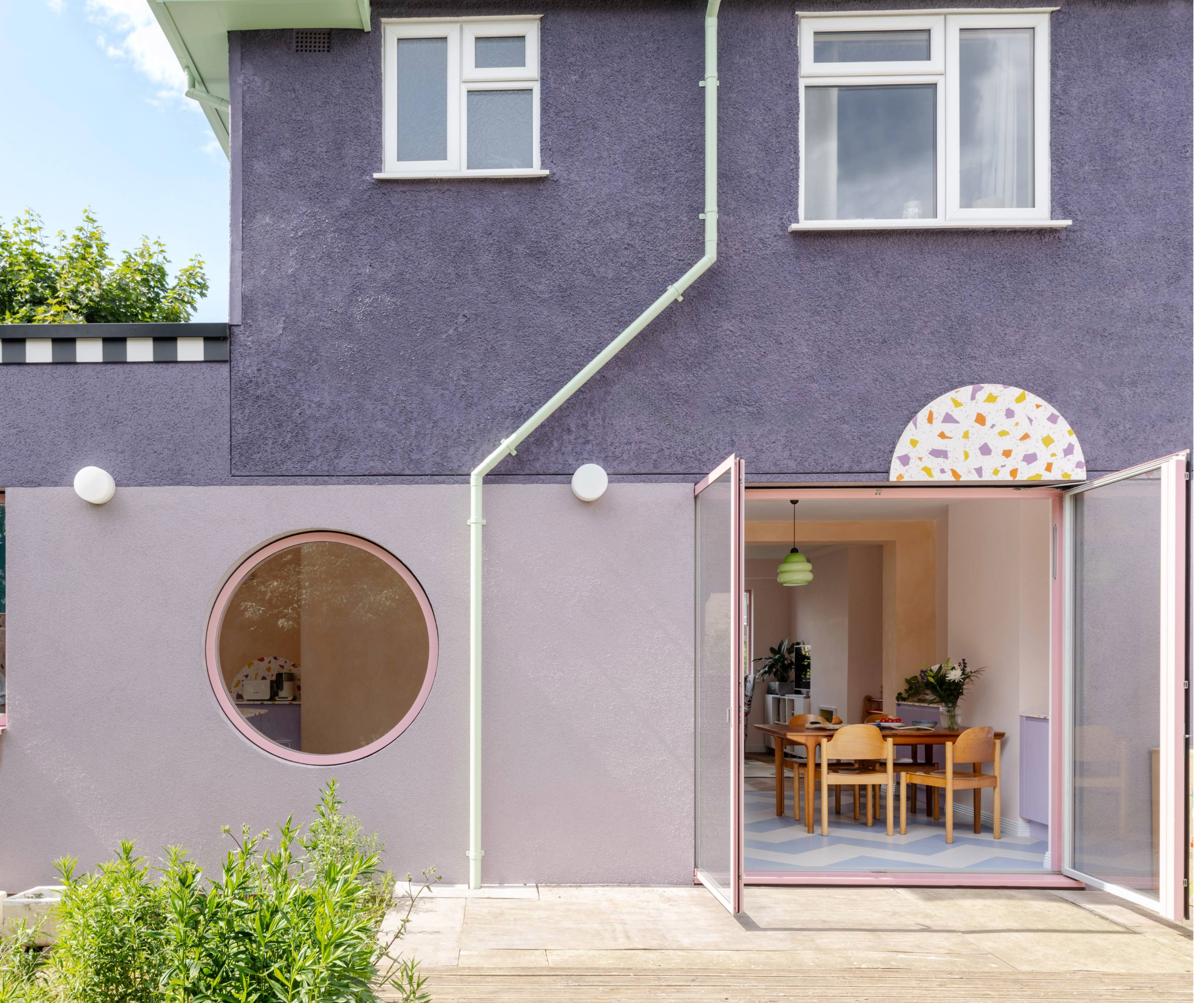 Exterior of the house from the back garden, featuring patio doors and a circle window