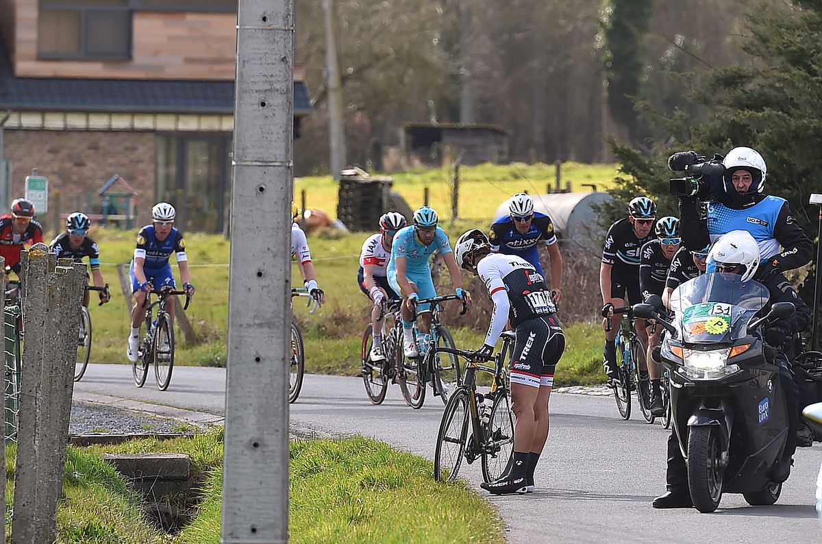 Fabian Cancellara waits for the team car after a mechanical as his rivals watch on