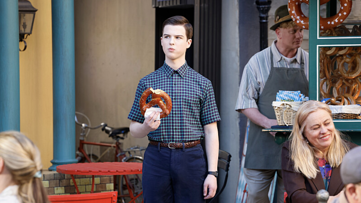 Sheldon Cooper (Iain Armitage) eating a pretzel outside a German cafe in &#039;Young Sheldon&#039; season 7