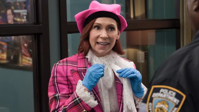 Carrie Preston looking excited and holding her hands up while wearing blue plastic gloves on Elsbeth.