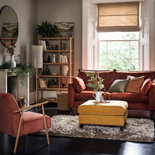 neutral living room with red velvet sofa and yellow footstool