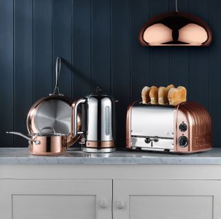 A copper coloured toaster, kettle, and pans on a kitchen counter