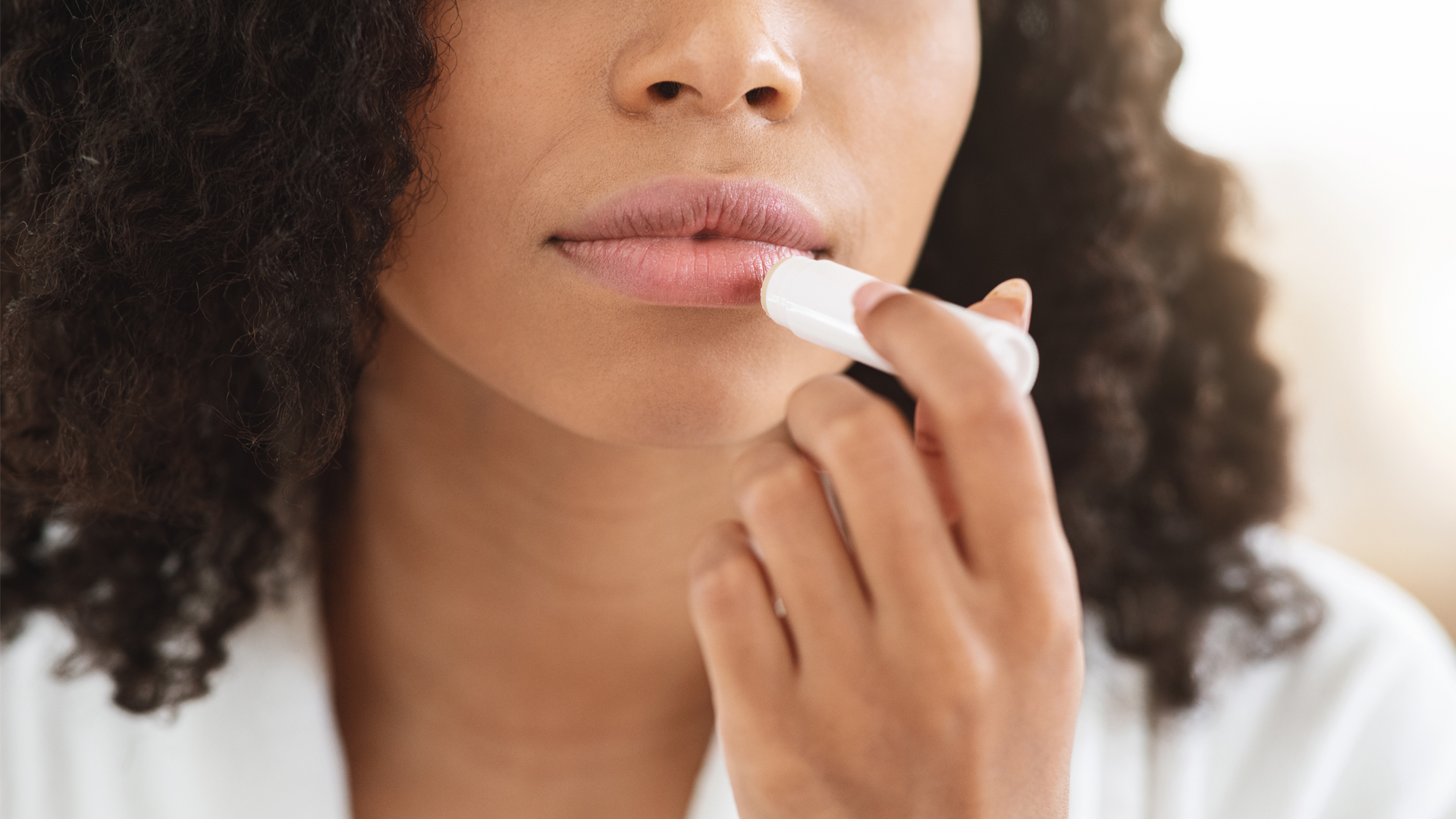 Close-up of a woman applying moisturizing lip balm with chapstick