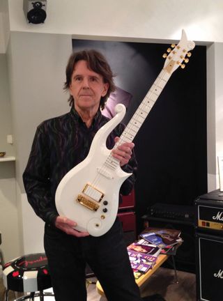 Dave Rusan holds a white Cloud guitar