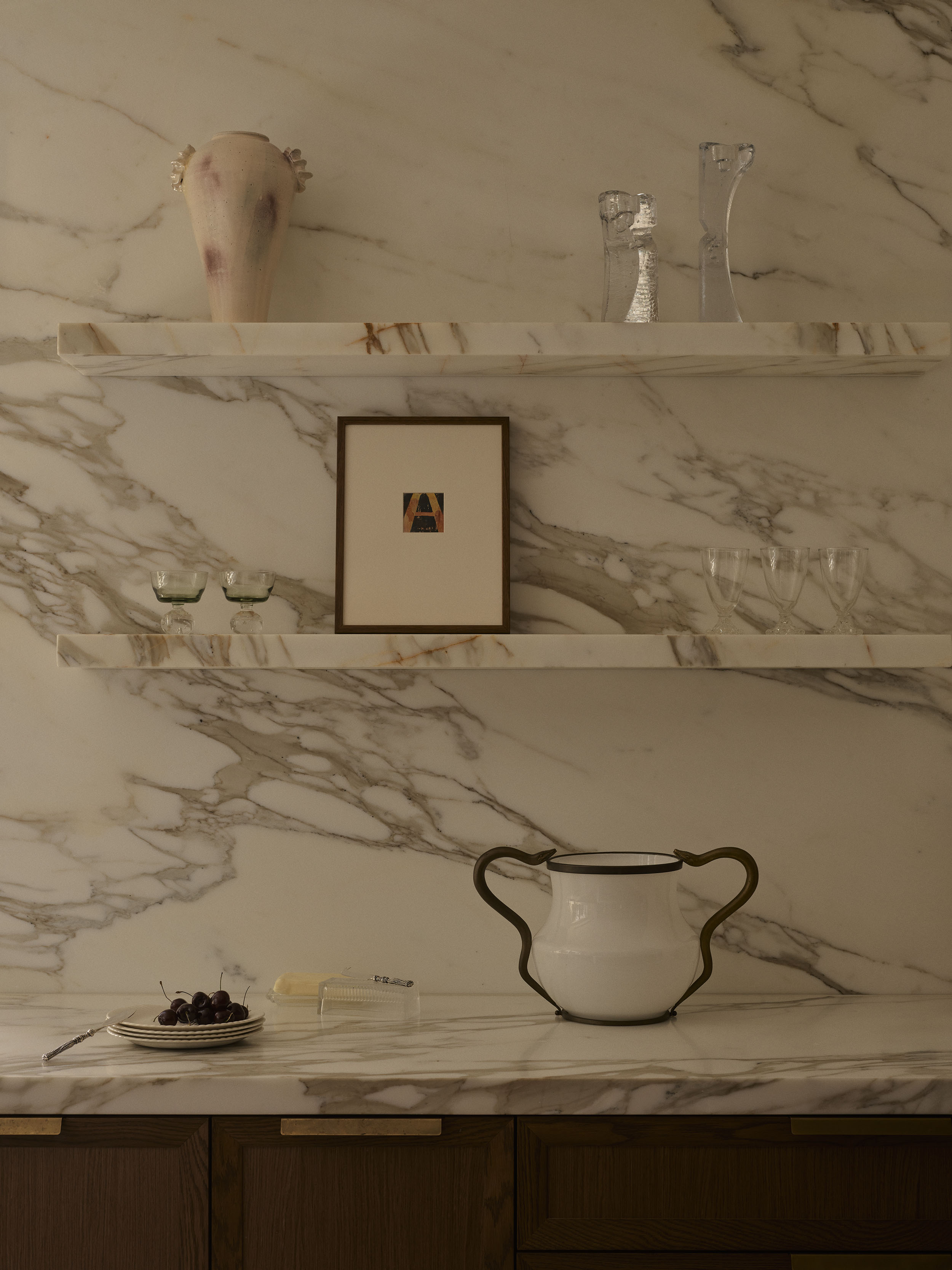 Calacatta Oro marble kitchen shelving displaying handcrafted ceramics, vintage glassware and artwork above warm timber cabinetry in Smac Studio's renovated Art Deco home in Woollahra, Sydney.