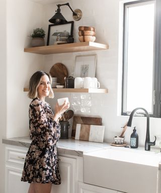 Designer Lauren Meichtry stands in the kitchen of her Manhattan Beach home, flanked by open shelving units, a large window and sink unit
