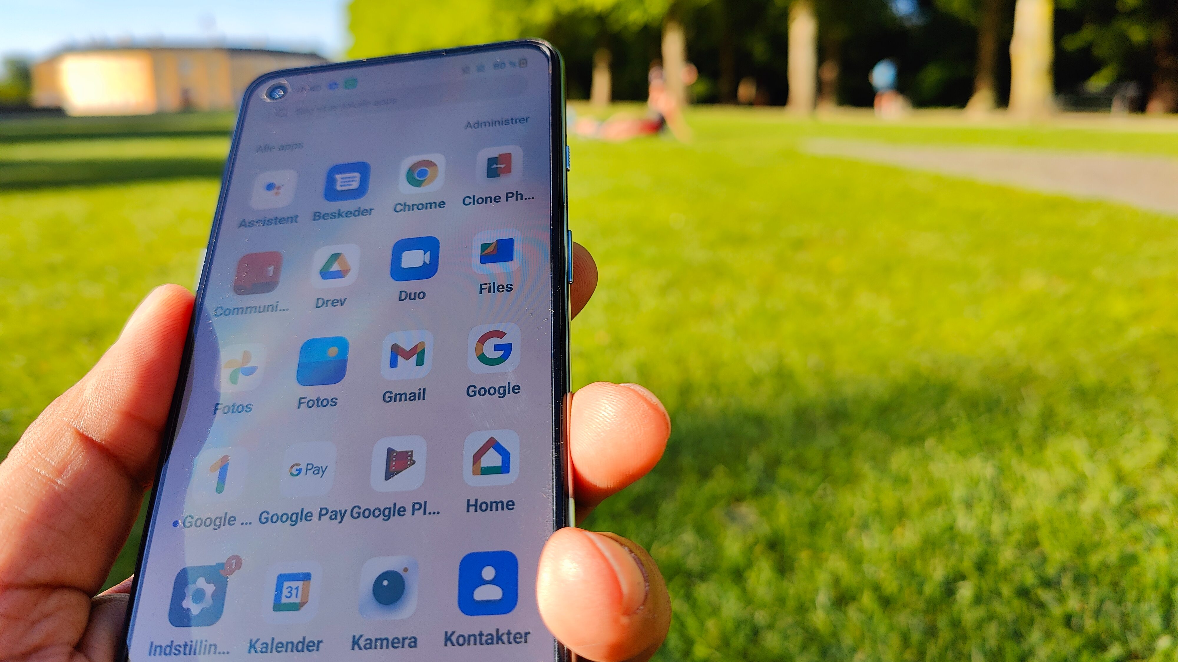 En hånd holder OnePlus Nord 2T udendørs i en park