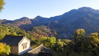 a temple in the foreground with trees and mountains in the background