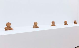 Clear thumb-prints are left in a line of clay portraits .