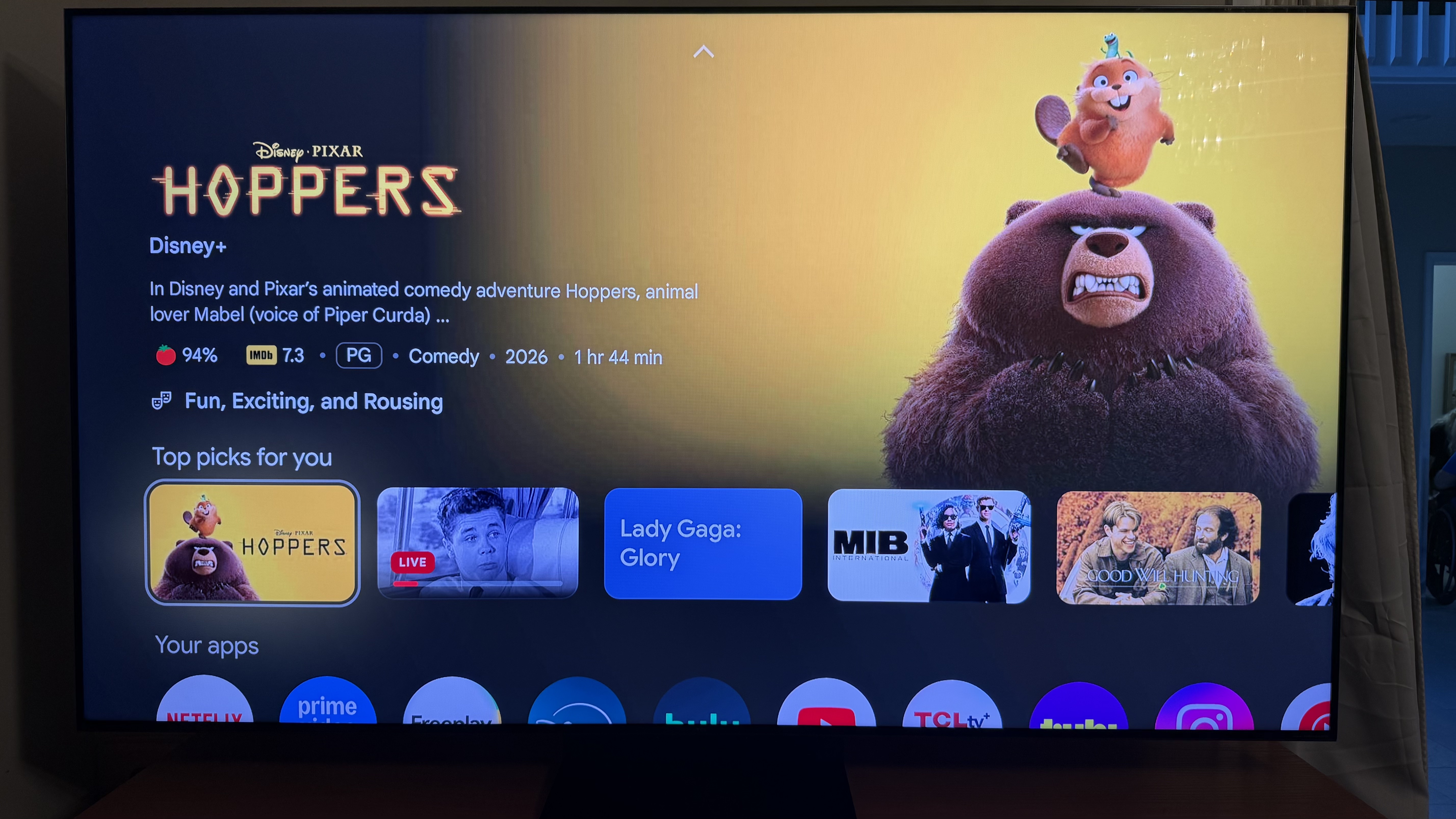 The TCL QM7L's Google TV home page shows a rotating banner of suggested content.