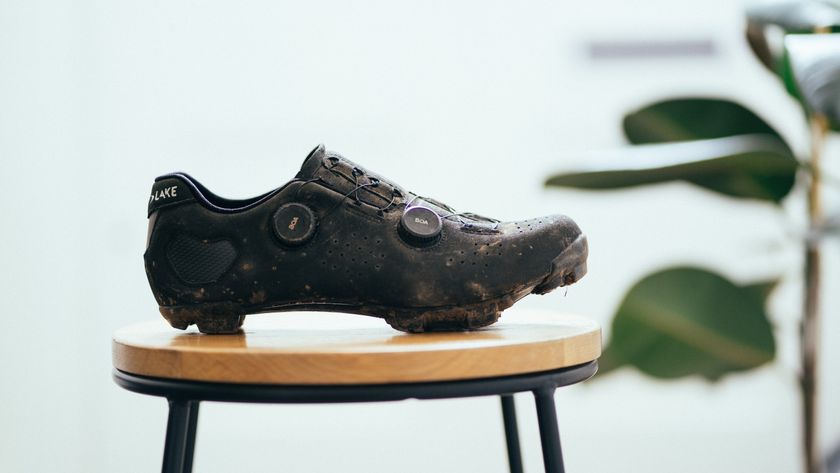 A black gravel shoe on a wooden stool against a white background