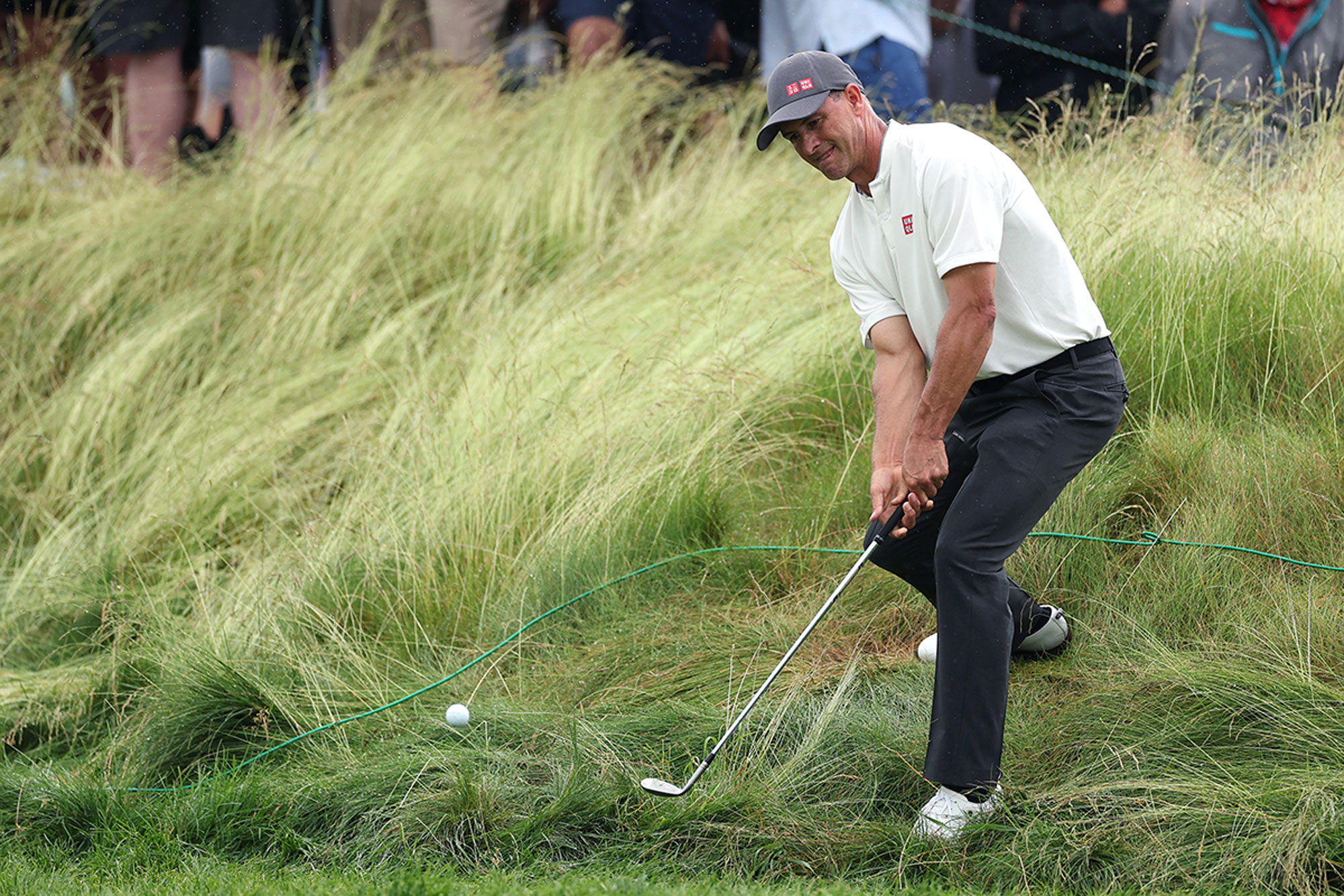 Adam Scott playing a very difficult shot from long grass at Oakmont Country Club during the 2025 US Open, barely getting his ball out with his chip shot around the green