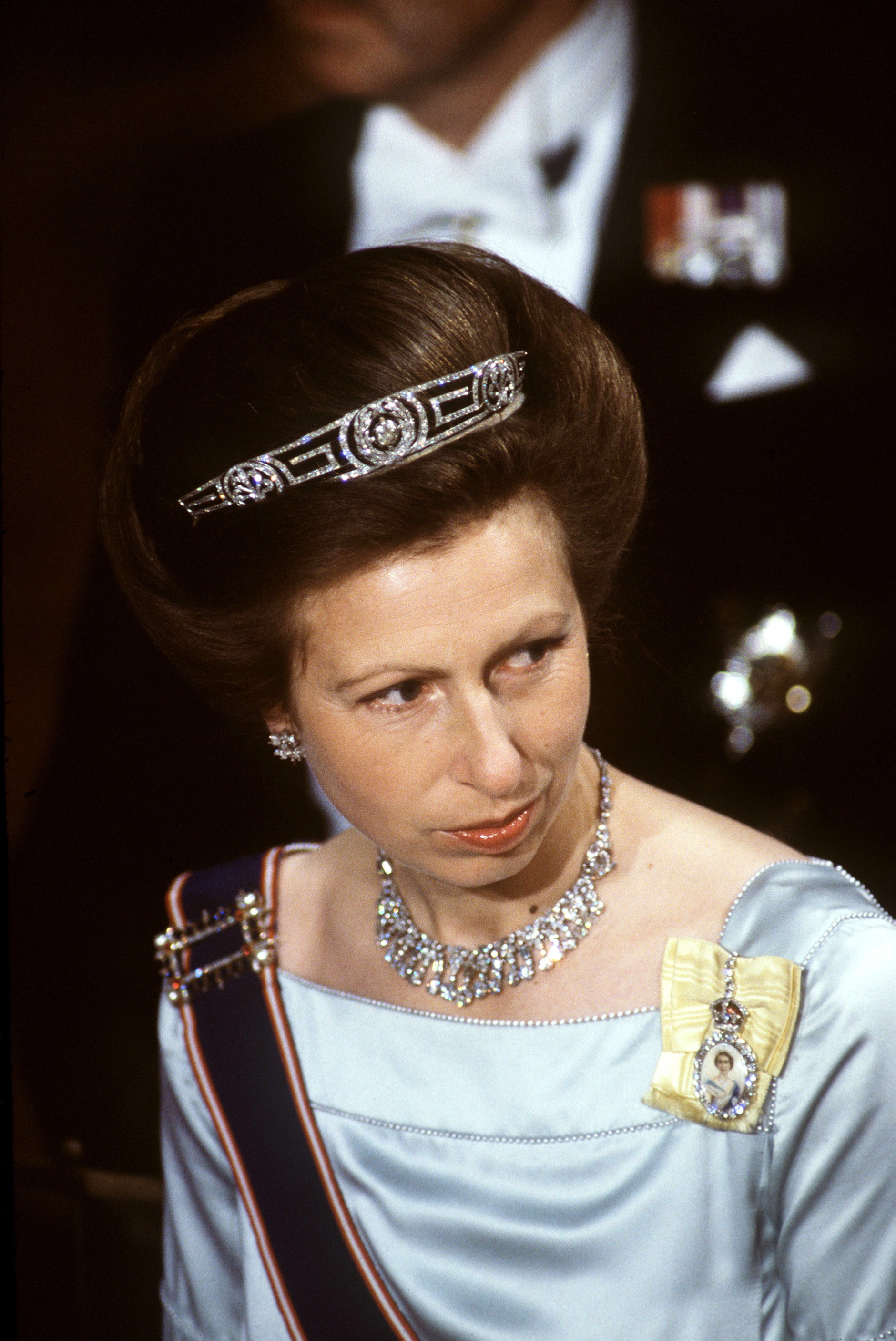 Princess Anne wearing a blue gown and diamond tiara looking skeptical