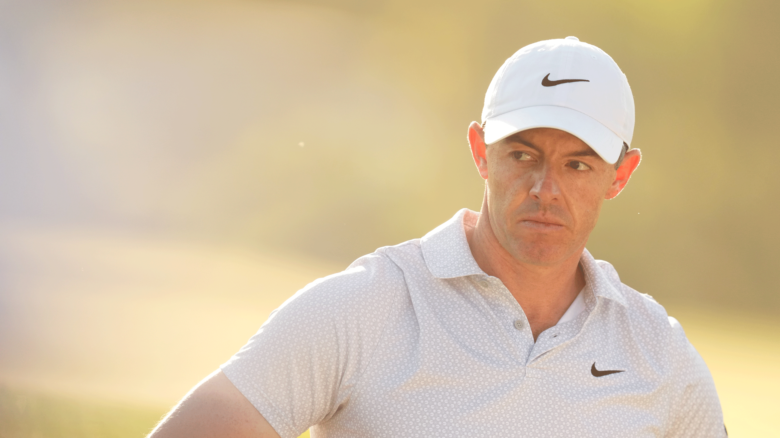 Rory McIlroy looks on during round two of The Masters in 2026 while wearing a white Nike cap and light polo shirt