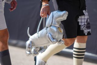 a guest at fashion month carrying a thom browne bag shaped like a daschund