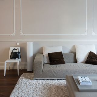 living room with white wall grey sofa with white and brown cushion wooden flooring and chair