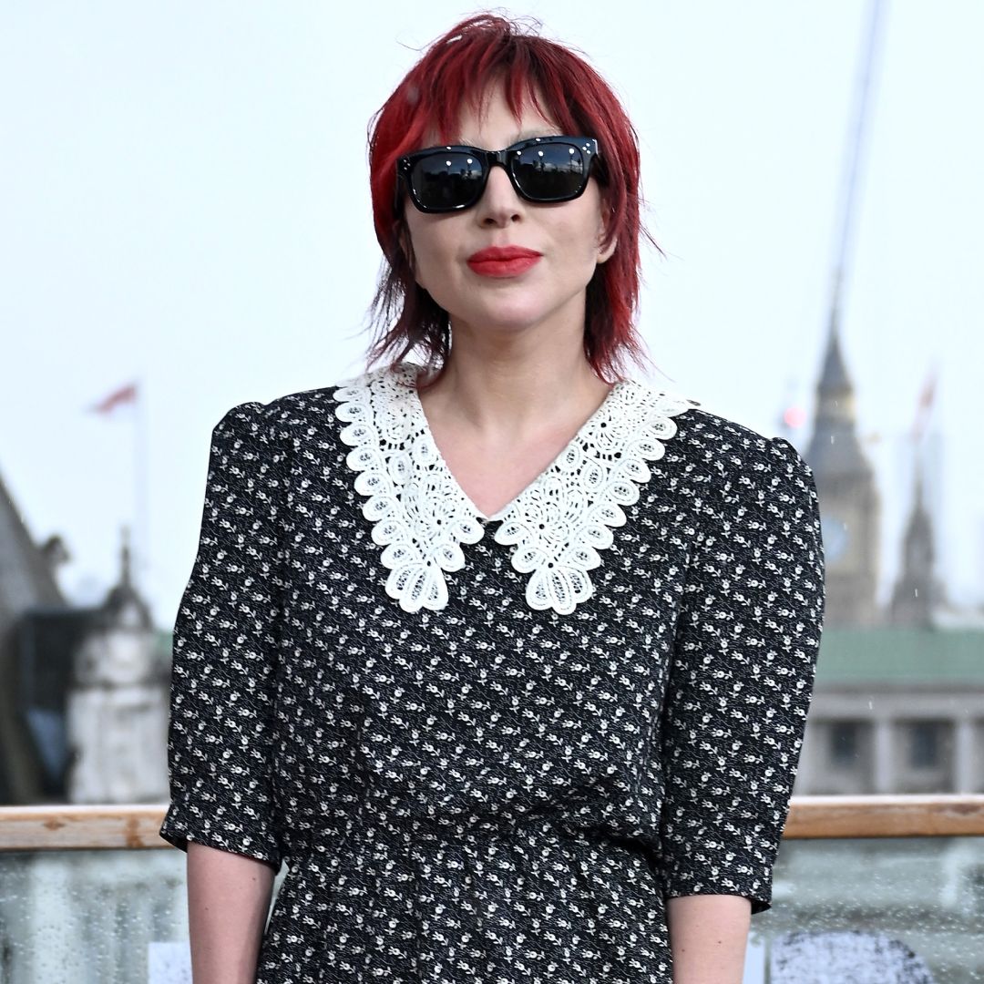 A woman with red hair wearing black sunglasses and a black and white shirt