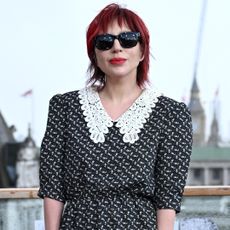 A woman with red hair wearing black sunglasses and a black and white shirt