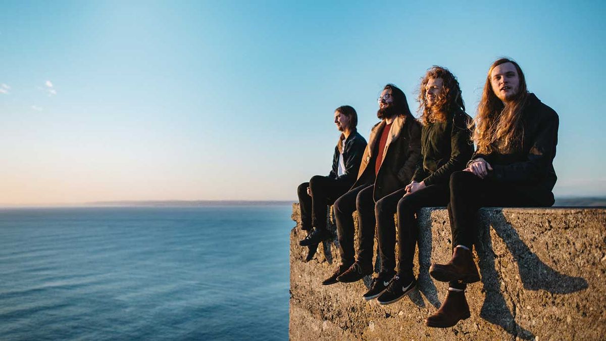 Haunt The Woods sitting on the edge of a cliff with the sea behind them