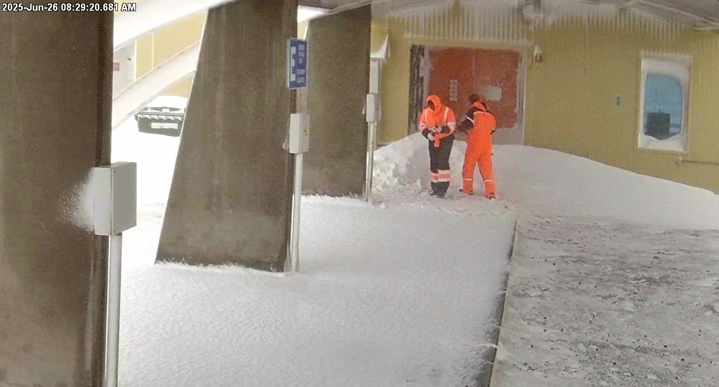 a grainy image of two men in snow suits working in a courtyard