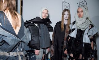 Models wear dresses and tops in black and grey with light blue hood and balaclava