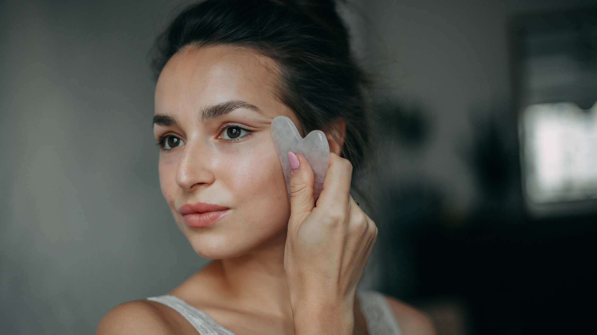 woman with glowing skin using a gua sha in her skincare routine