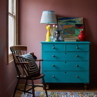 blue painted wooden chest of drawers and a bright yellow table lamp with blue patterned shade