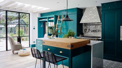 Kitchen with turquoise painted cabinetry and island and Crittal style doors