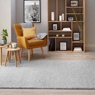 Dunelm's Pebble Wool Rug in grey on living room floor with armchair, bookcase and side table