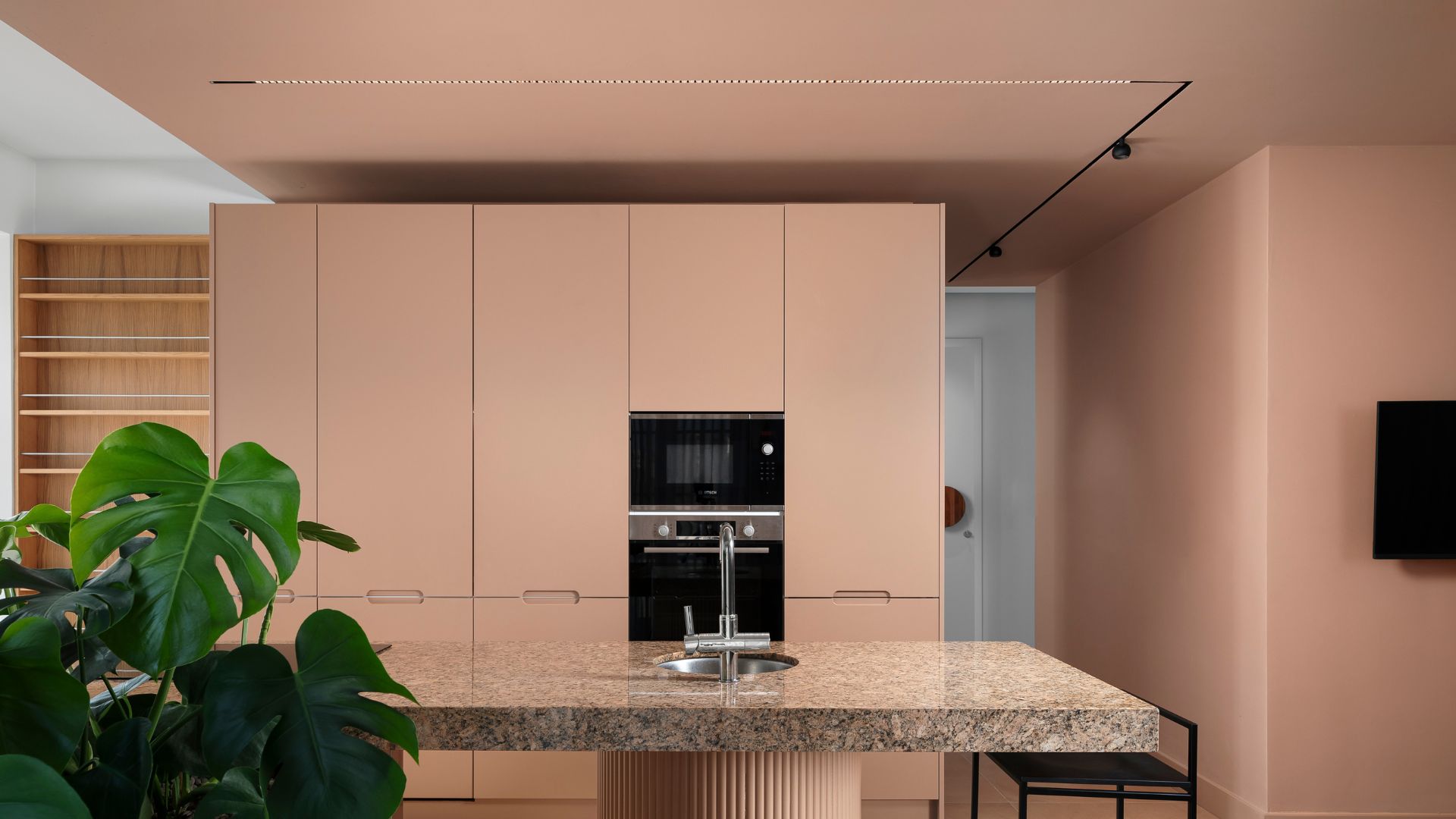 A kitchen drenched in pink, with overhead spotlights 