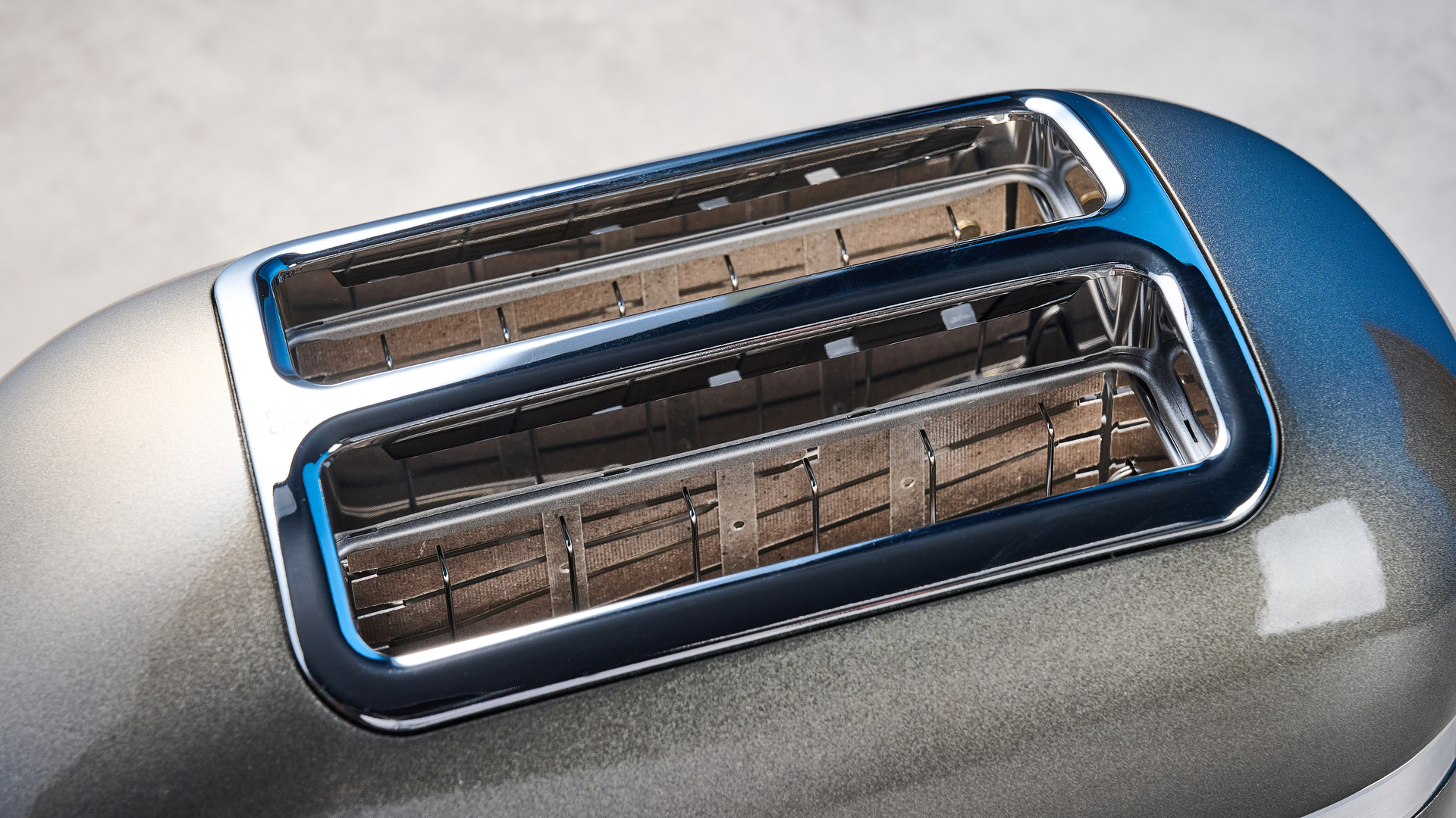 A photograph of the KitchenAid Pro Line toaster on a stone work surface with a blue and wooden background