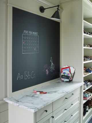 Chalkboard atop storage unit with marble with dedicated space for mail and shoes