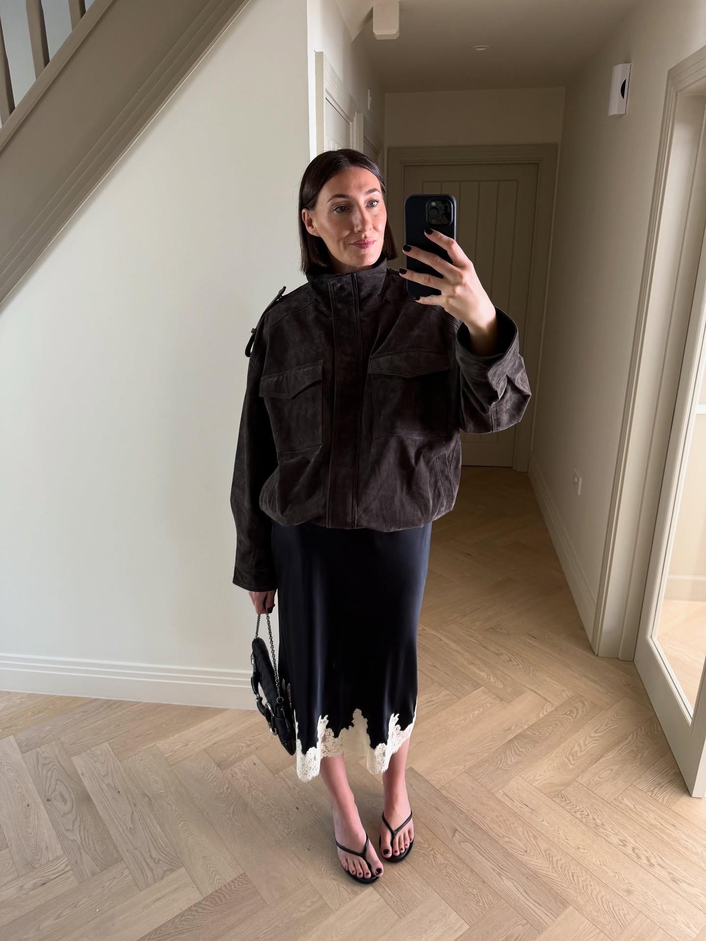 sarah louise blythe wears a funnel neck jacket, slip skirt and flip flops