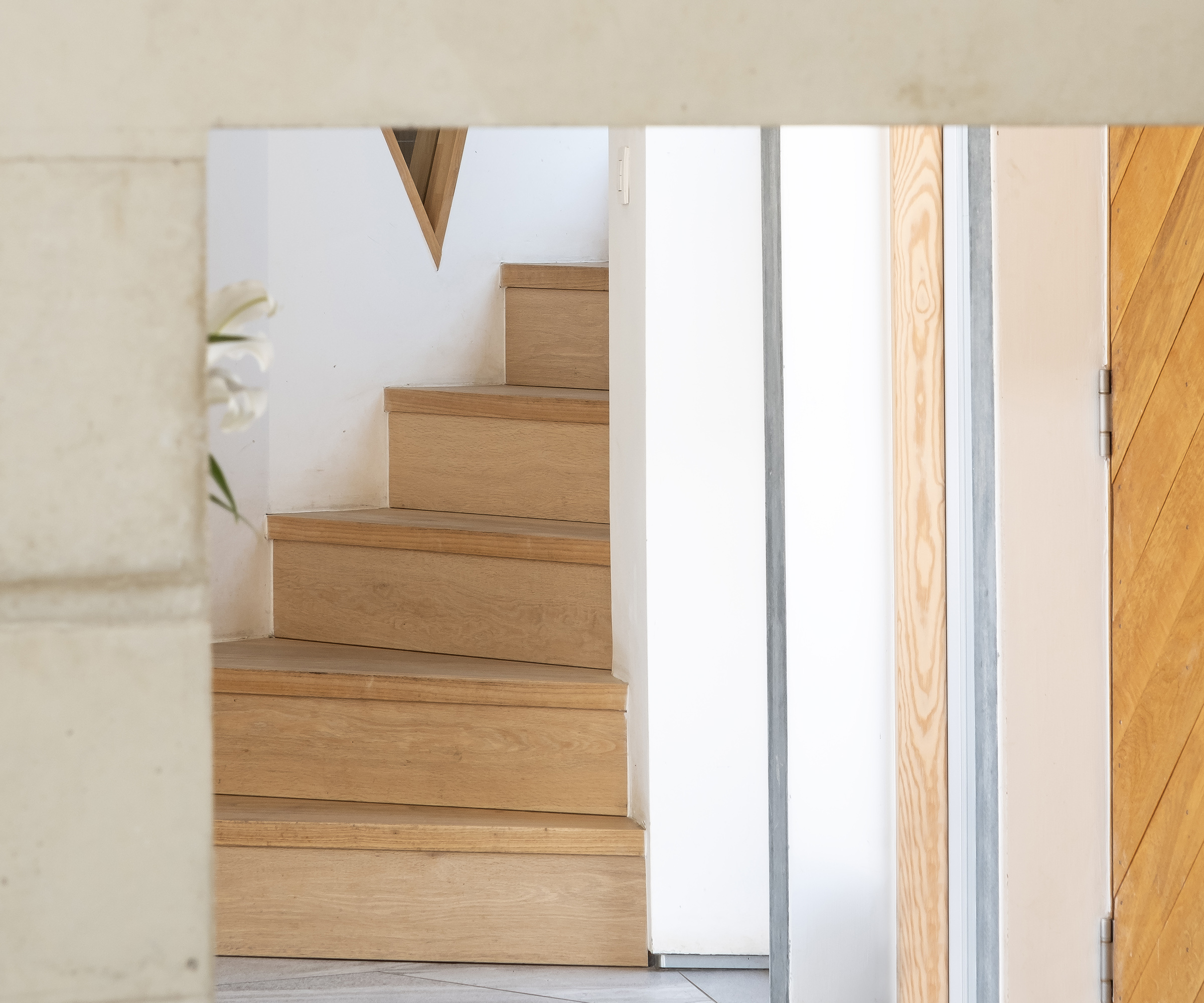 The glimpse of a contemporary timber staircase through a doorway in a self build home