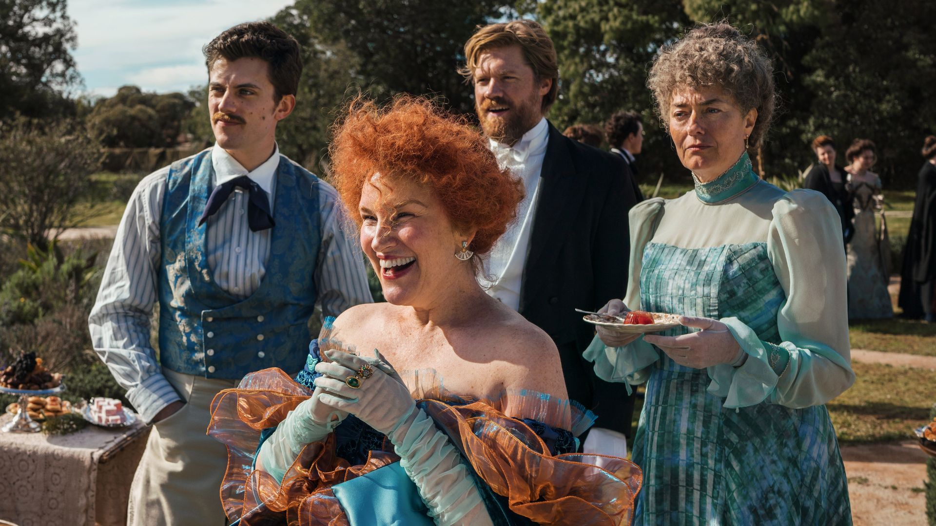 Two men and two women stand in a garden during a party