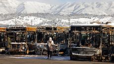 A woman inspects buses damaged during protests in Iran in January 2026