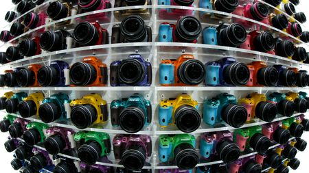 Ricoh Co. Pentax K-50 digital single lens reflex (DSLR) cameras sit on display at the CP+ Camera and Photo Imaging Show in this photograph taken with a fish-eye lens in Yokohama, Kanagawa Prefecture, Japan, on Thursday, Feb. 13, 2014