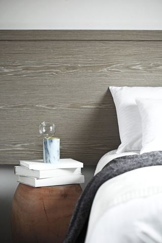 A marble pillar with glass globe balanced on top, sits on a bedside table