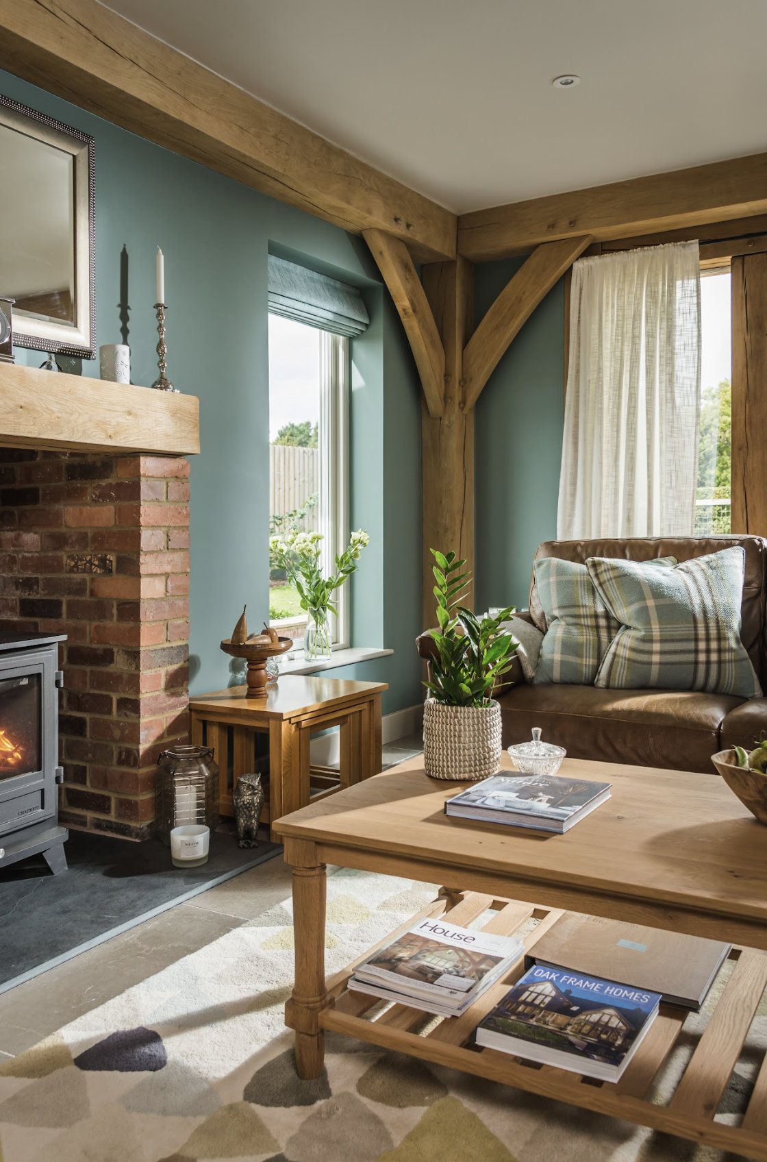 A living room with a brick fireplaces, exposed wooden beams and blue painted walls